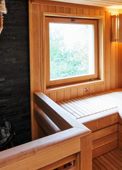 Metal stove filled with stones with a chimney in the sauna near the wooden benches by the window. High quality photo